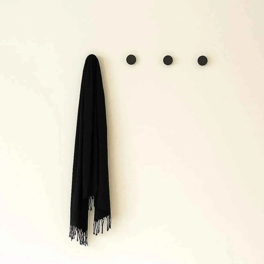 Matte black round wall hooks, three in a row with a black fringed scarf on one
