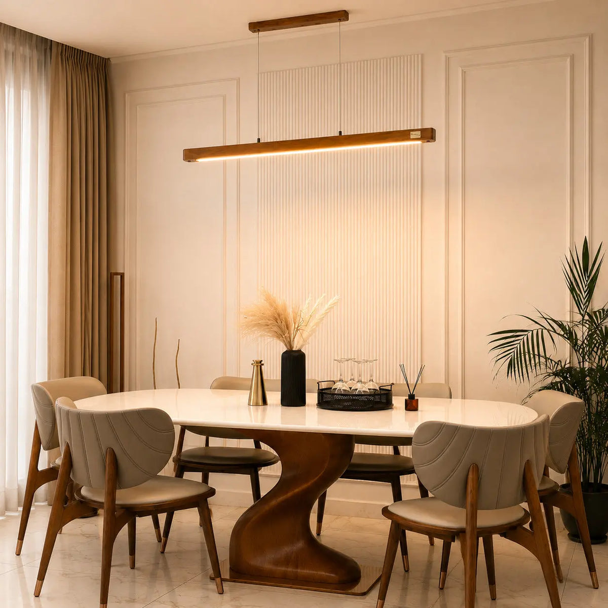 Teak wood pendant light lit over a dining table beside tall curtained windows