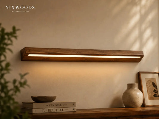 NixWoods natural teak linear wall light lit above a wooden console with books and a ceramic vase
