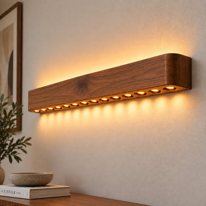 Angled close-up of the circular cut-outs in the wooden wall light, each holding a warm LED