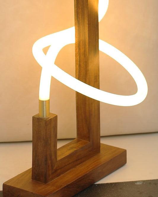 Detail of the sculpted glow floor lamp base, showing solid wood joinery, visible grain and the brass sleeve where the LED rope enters the frame