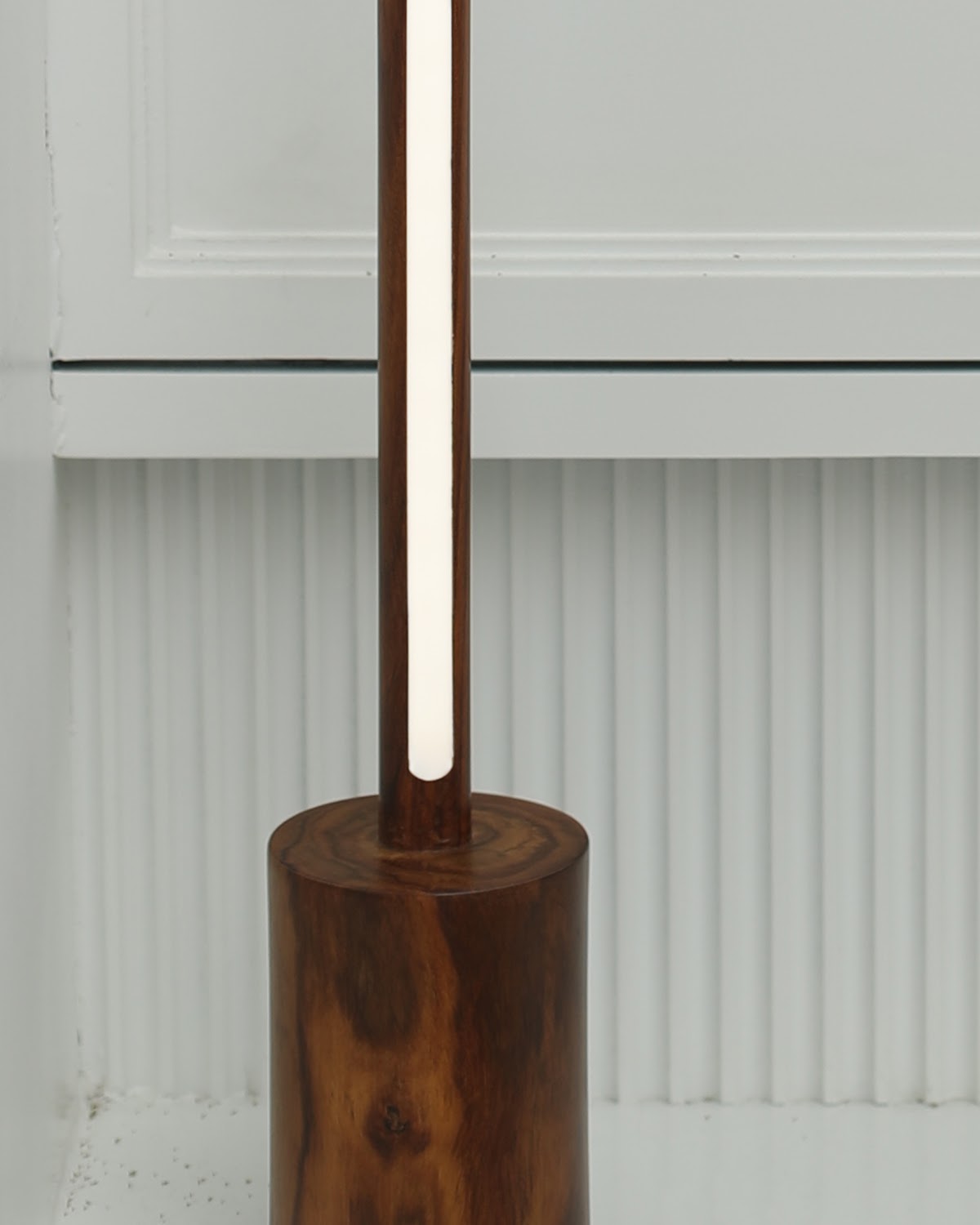 Close-up of the round turned solid wood base of the minimal tall floor lamp, showing natural grain and figure in the timber