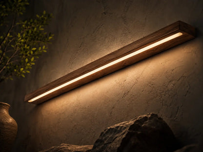 Close angled view of the NixWoods teak linear wall light glowing on a textured dark wall