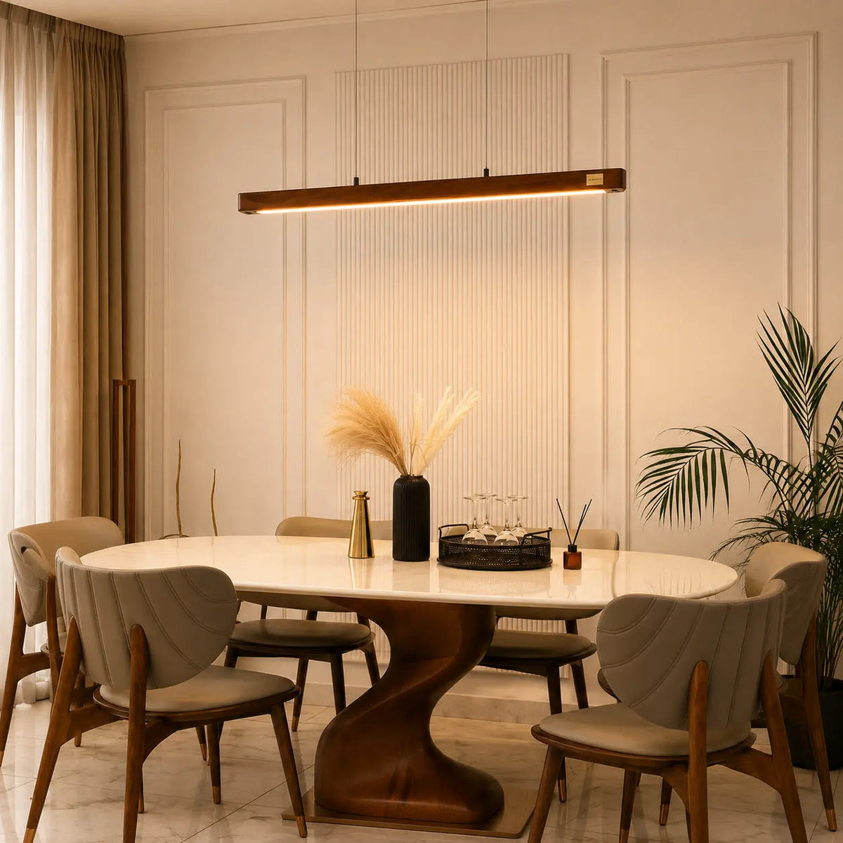 Wooden linear pendant light in a dining room with tall curtains and an oval marble table