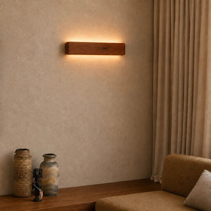 Rosewood wall light glowing above a seating nook with ceramic vases and linen curtains