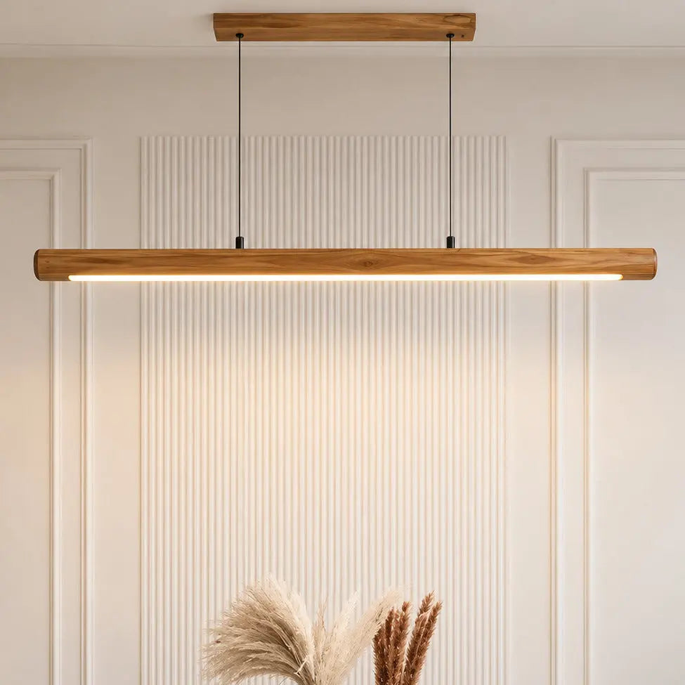 Rosewood linear pendant lit over a white dining table against a fluted panel wall