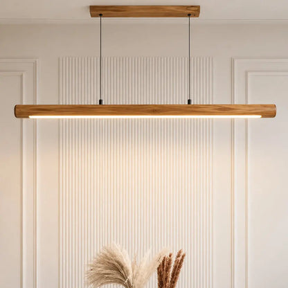 Rosewood linear pendant lit over a white dining table against a fluted panel wall