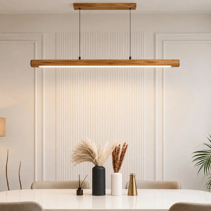 Rosewood linear pendant light glowing above a dining table with pampas grass and a brass vase — NixWoods