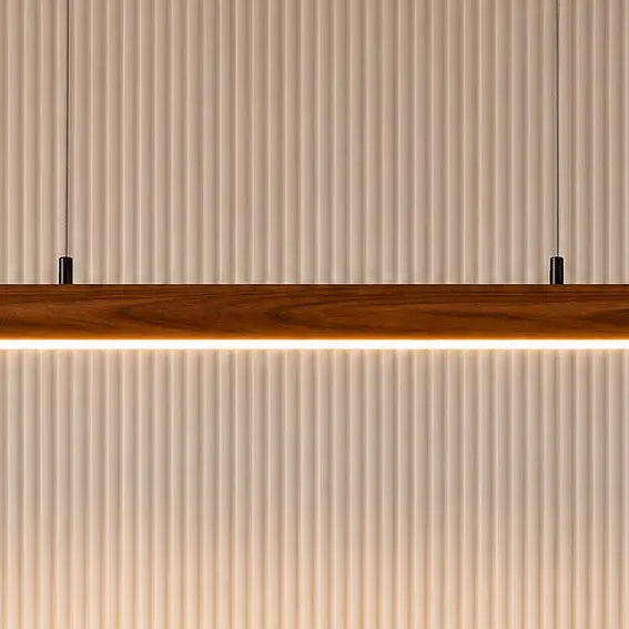 Close-up of the rosewood pendant's warm LED strip underside against a fluted white panel
