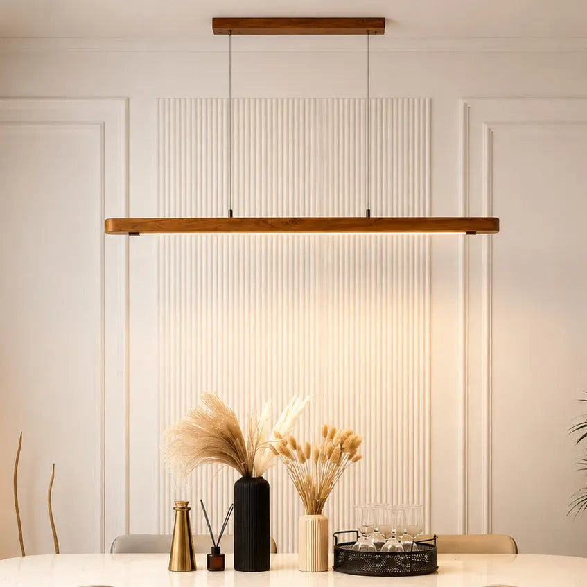 Teak linear pendant light lit above a dining table with pampas grass and glasses — NixWoods