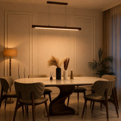 Rosewood cylindrical pendant lit in the evening over a dining table with six chairs