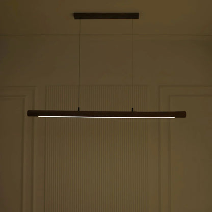 Rosewood linear pendant light casting warm light in a dim panelled room - NixWoods hanging light