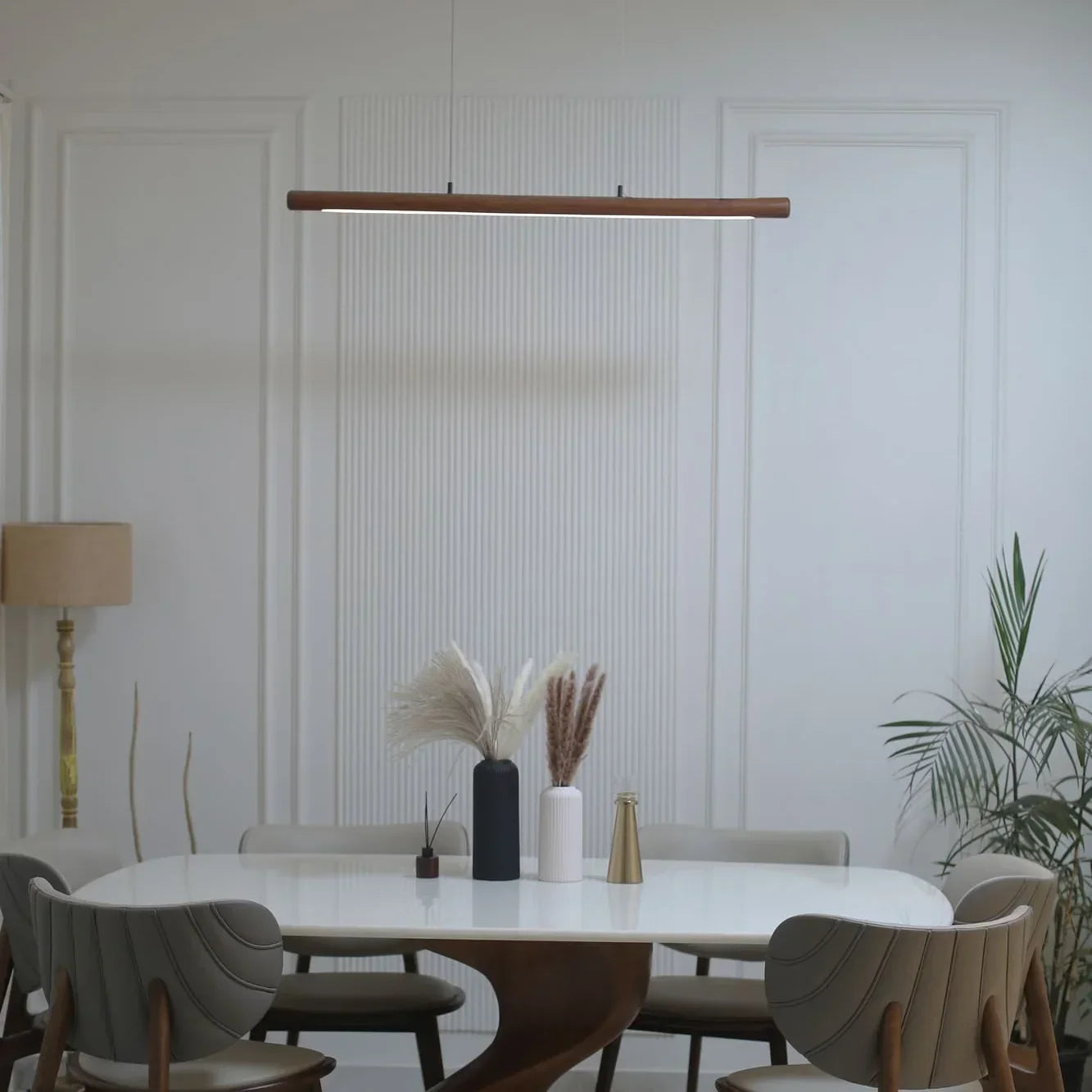 Linear wooden pendant light glowing above a round dining table - NixWoods handcrafted hanging light