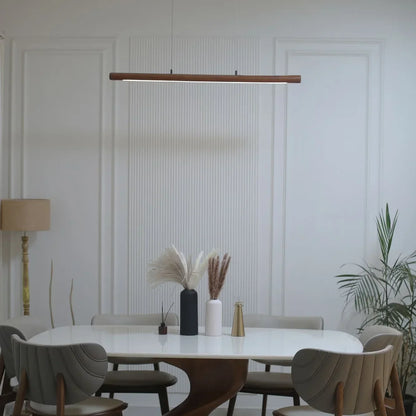 Linear wooden pendant light glowing above a round dining table - NixWoods handcrafted hanging light
