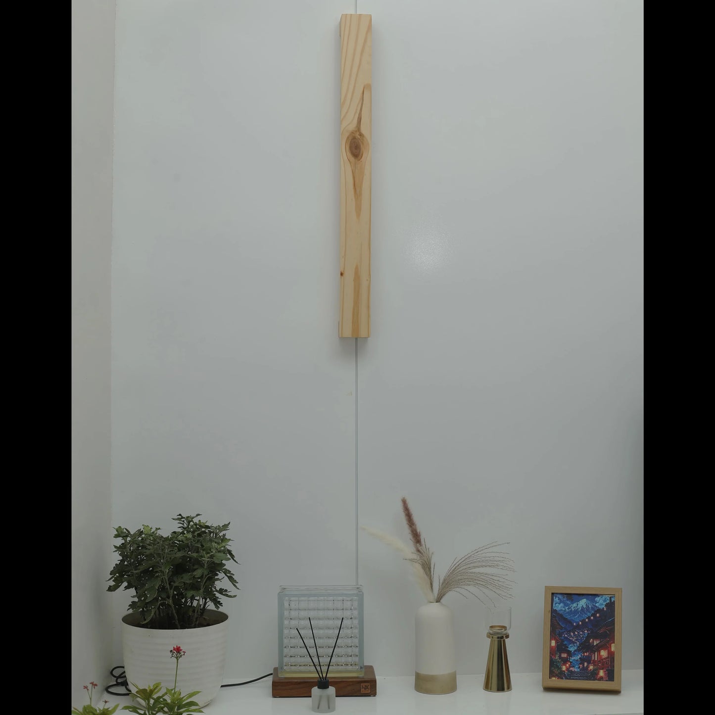 Nix Line pale wood wall light mounted vertically above a console with plants - NixWoods wall sconce