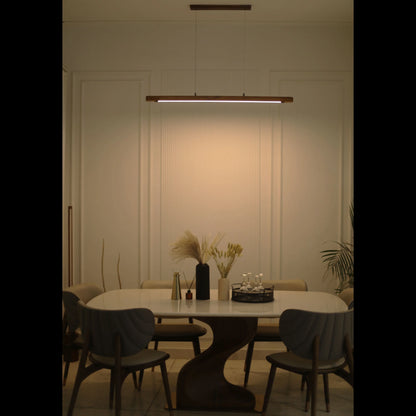 Teak linear pendant light lit above a dining table in a dark room - NixWoods hanging light