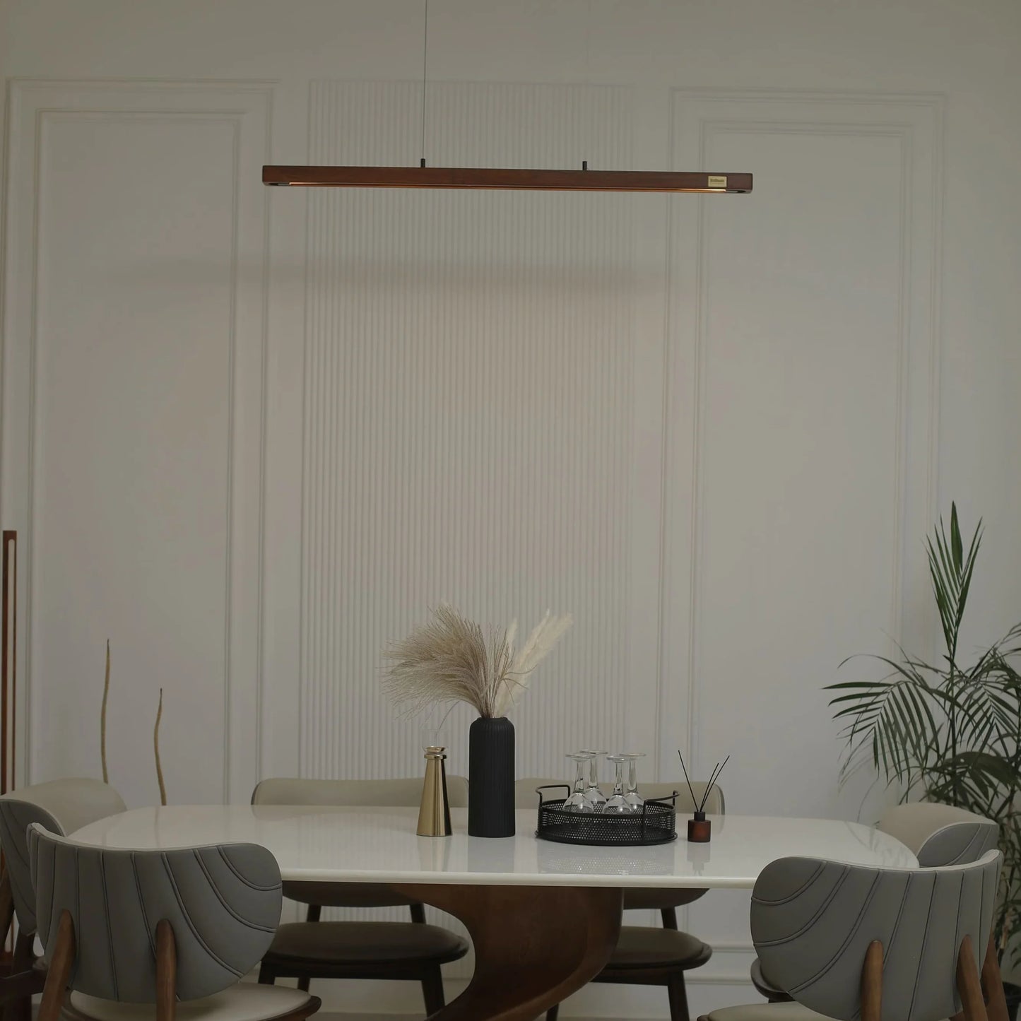 Wooden linear pendant light above a dining table with vase and plant - NixWoods hanging light