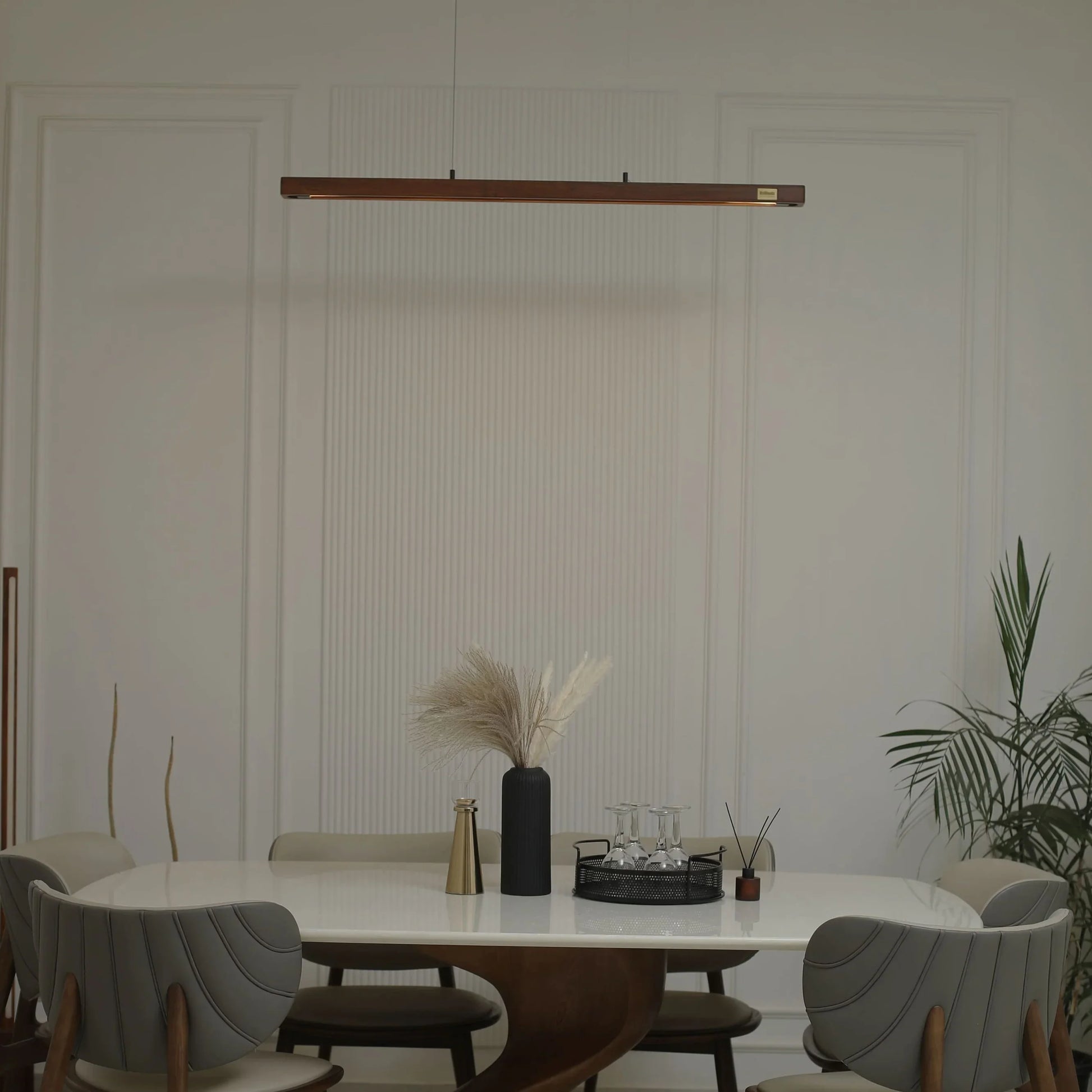 Wooden linear pendant light above a dining table with vase and plant - NixWoods hanging light