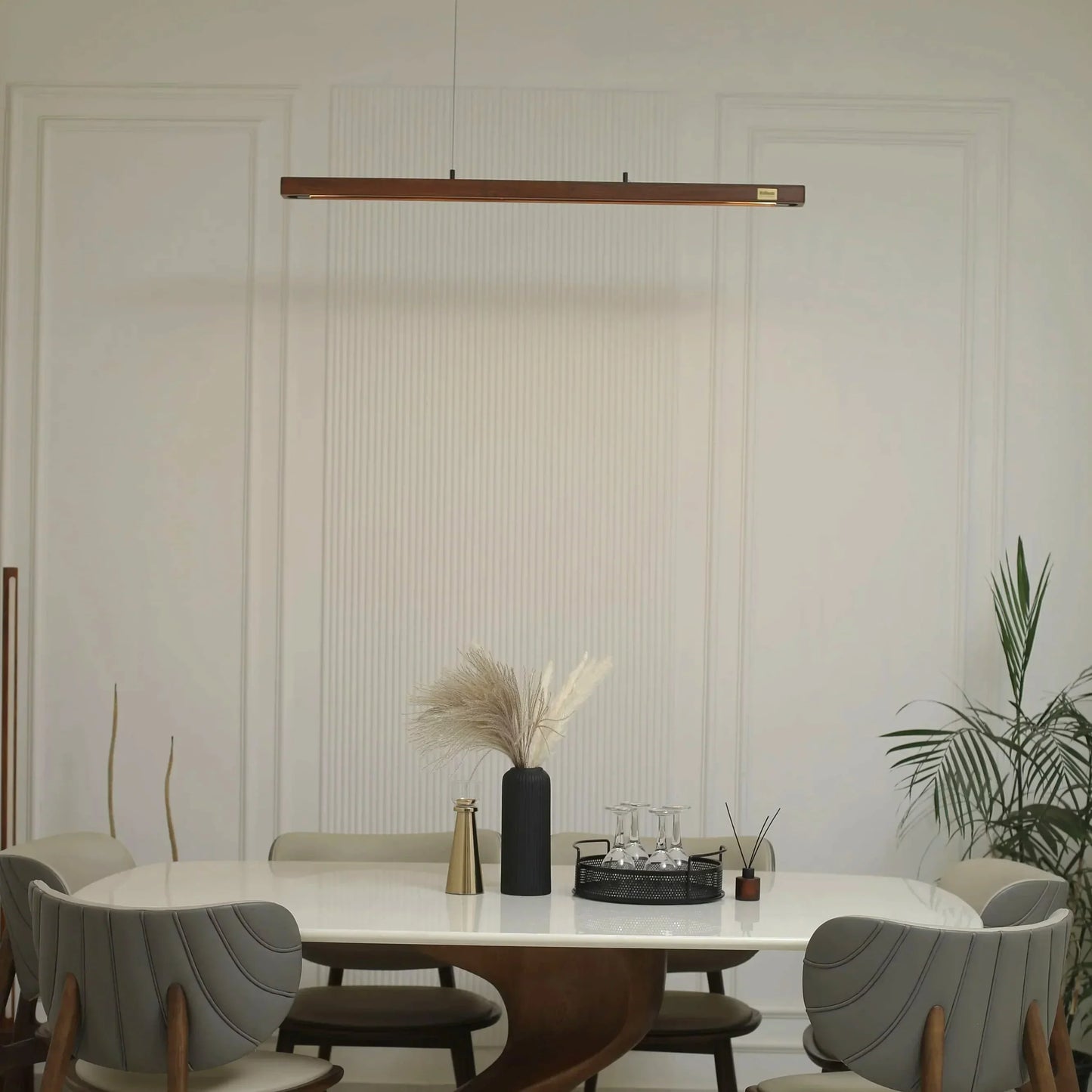 Wooden linear pendant light lit above a dining table - NixWoods handcrafted ceiling hanging light