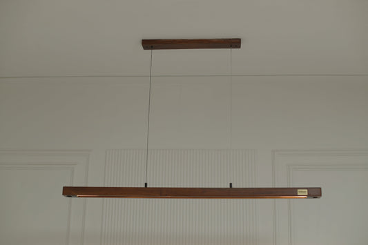 A minimalist modern door handle set featuring two dark brown wooden posts connected by a thin horizontal wire, mounted on a white paneled door.