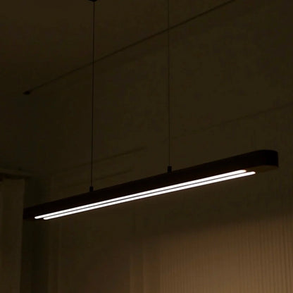 Wooden linear pendant light glowing in a darkened dining room - NixWoods handcrafted hanging light