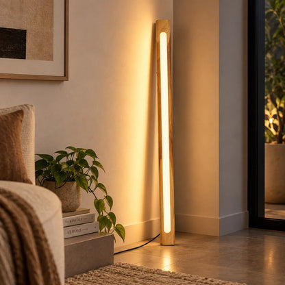 Solid teak leaning floor lamp glowing warm beside a sofa and a potted plant - NixWoods