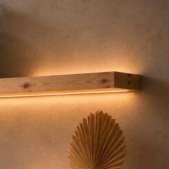 Pine floating wall light shelf glowing warm above a paper-fan wall decoration