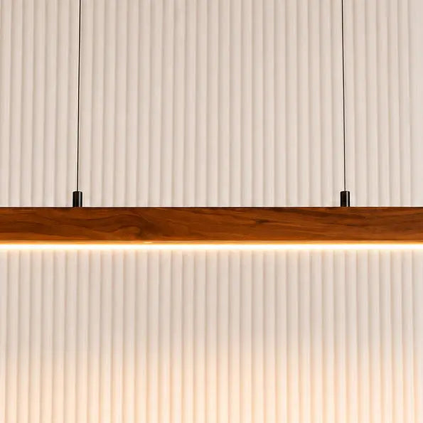 Close-up of the warm white LED strip under the teak pendant bar against a fluted wall