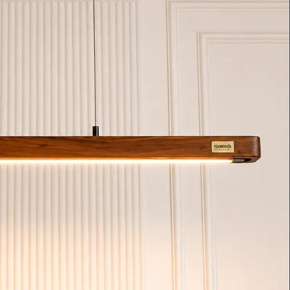 Close-up of teak grain and brass NixWoods plaque on the linear pendant bar