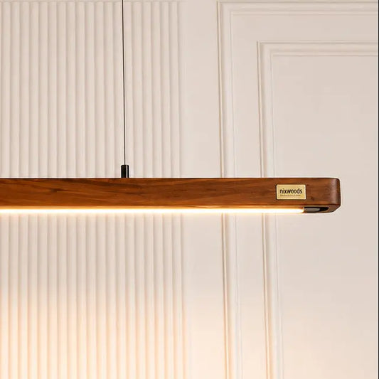 Close-up of teak grain and brass NixWoods plaque on the linear pendant bar