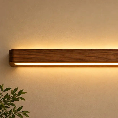Close-up of dark teak grain and the continuous warm LED strip running the length of the wall light