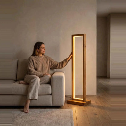 Teak rectangular floor lamp shown for scale beside a woman seated on a living room sofa