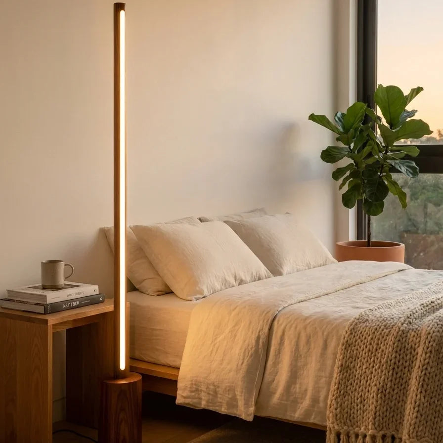 Minimalist rosewood floor lamp beside a low bed in a bright serene bedroom with cream bedding, wood side table and plant – NixWoods