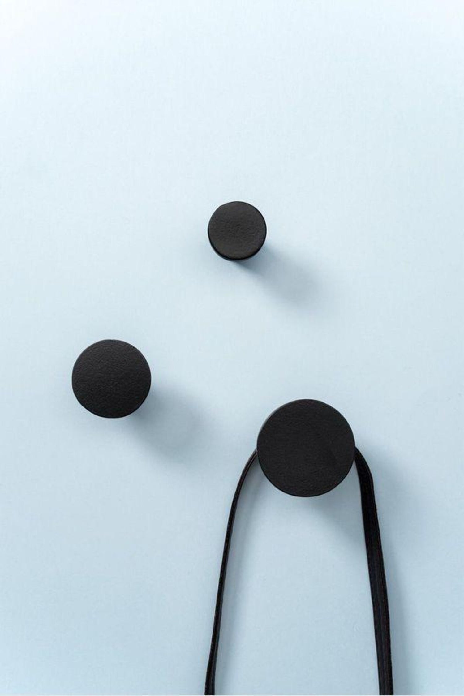 Black earbud headphones on a light blue background