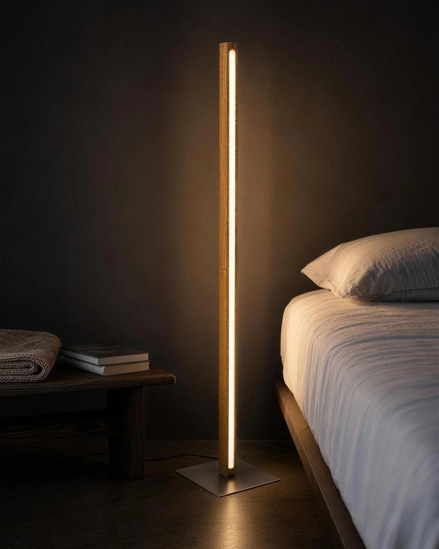Scandinavian Teak Linear Floor Lamp beside a bed at night as the only light in the room, warm glow along the teak column