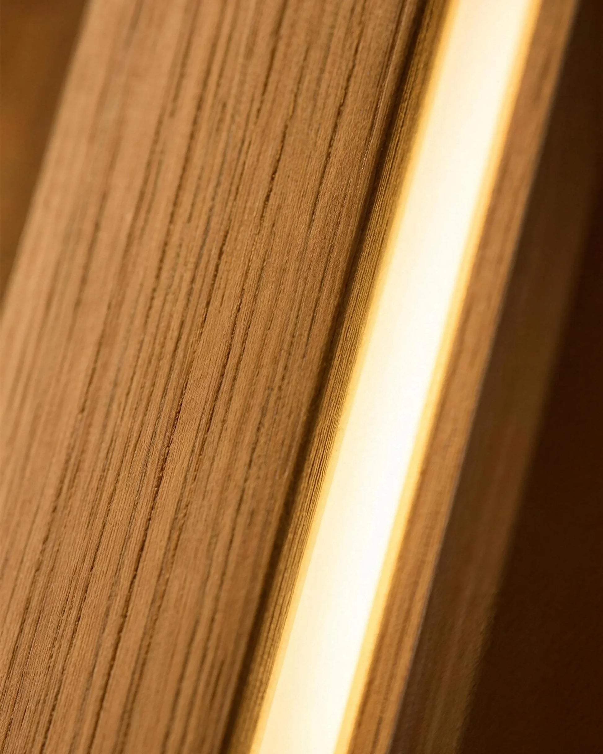 Close-up of the solid teak grain where the wood meets the recessed warm LED channel on the Scandinavian Teak Linear Floor Lamp