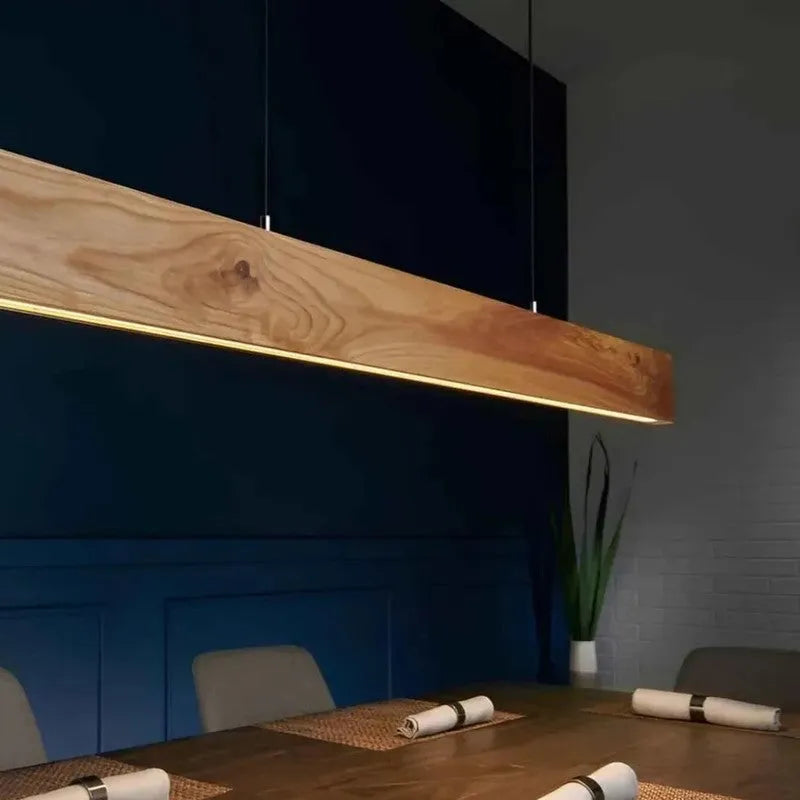 Pine wood pendant light lit above a dining table against a deep blue wall - NixWoods hanging light
