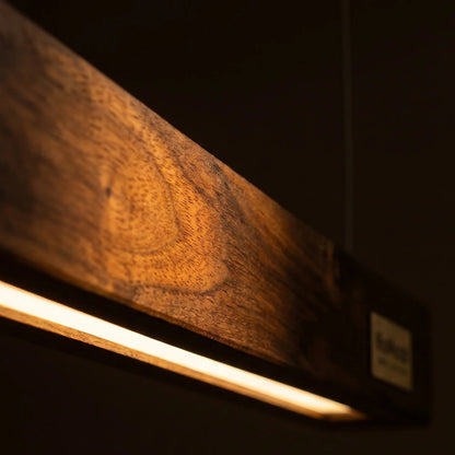 Close-up of the rosewood slats and warm glow of the NixWoods linear pendant light